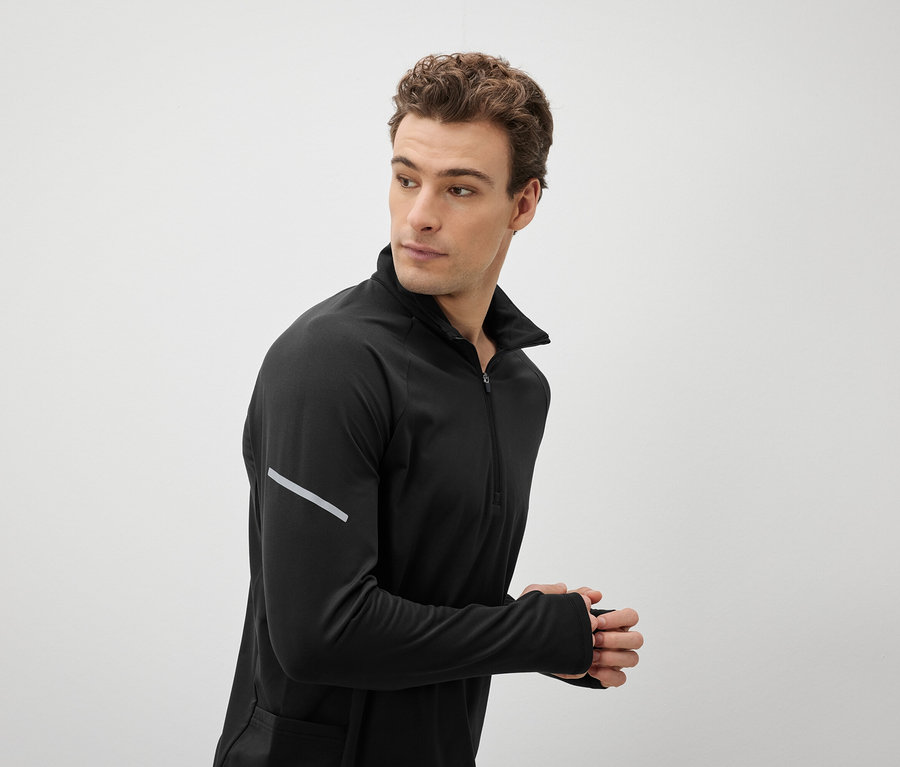 Mann in schwarzem Sportoberteil blickt über die Schulter.