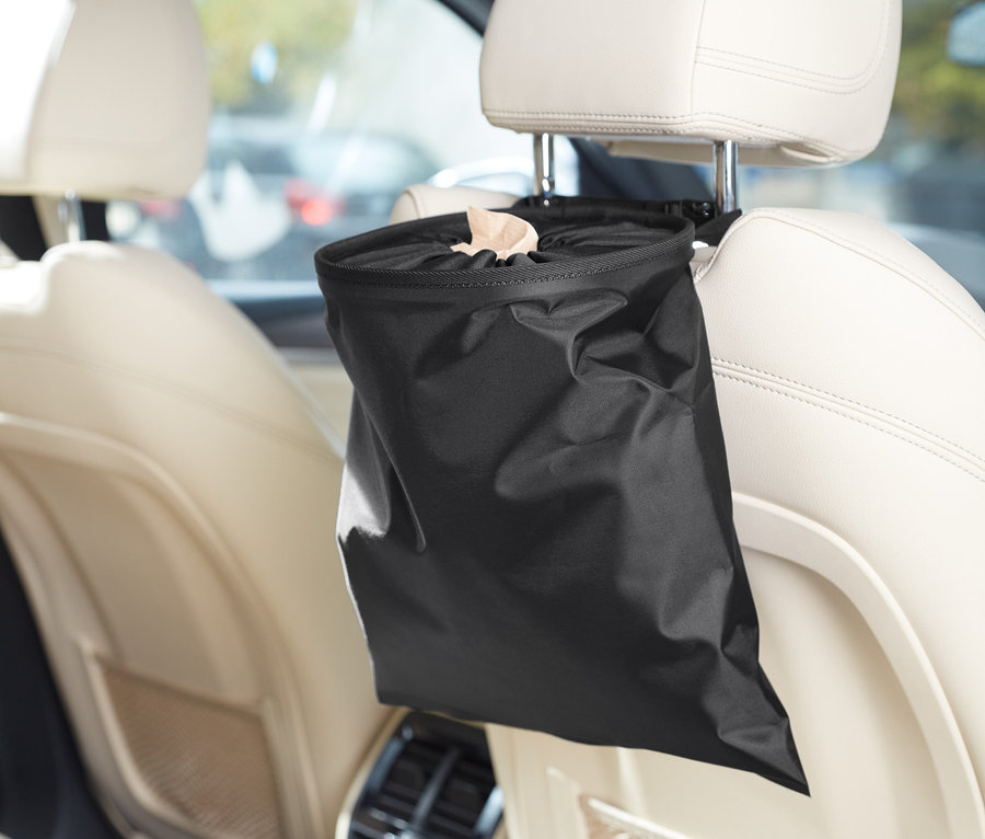Im Auto hängt ein schwarzer Universal-Mülleimer an der Kopfstütze des Sitzes.