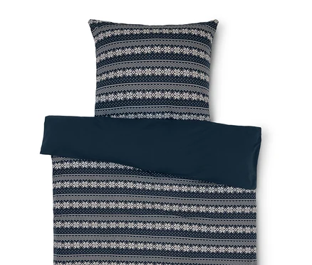 Bettwäsche mit blau-weissem Schneeflockenmuster und einfarbig blauem Bezug.