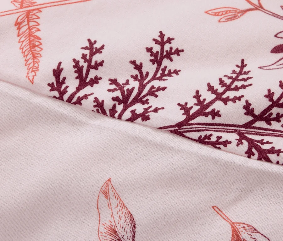 Nahaufnahme eines Stoffes mit Blatt- und Zweigmuster in Rosa- und Burgundertönen.