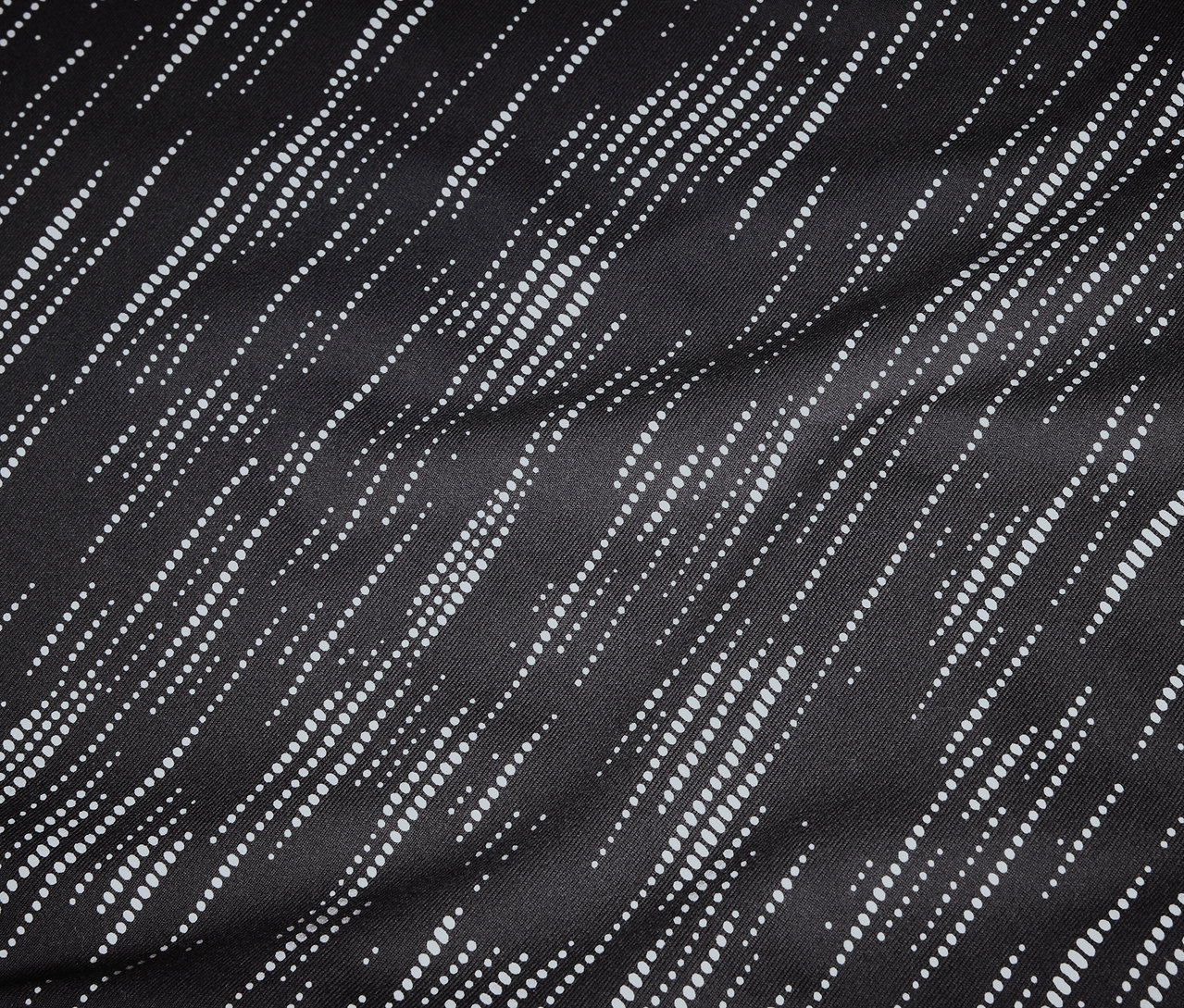 Detailaufnahme eines schwarzen Stoffes mit diagonalen, gepunkteten, weißen Linien.