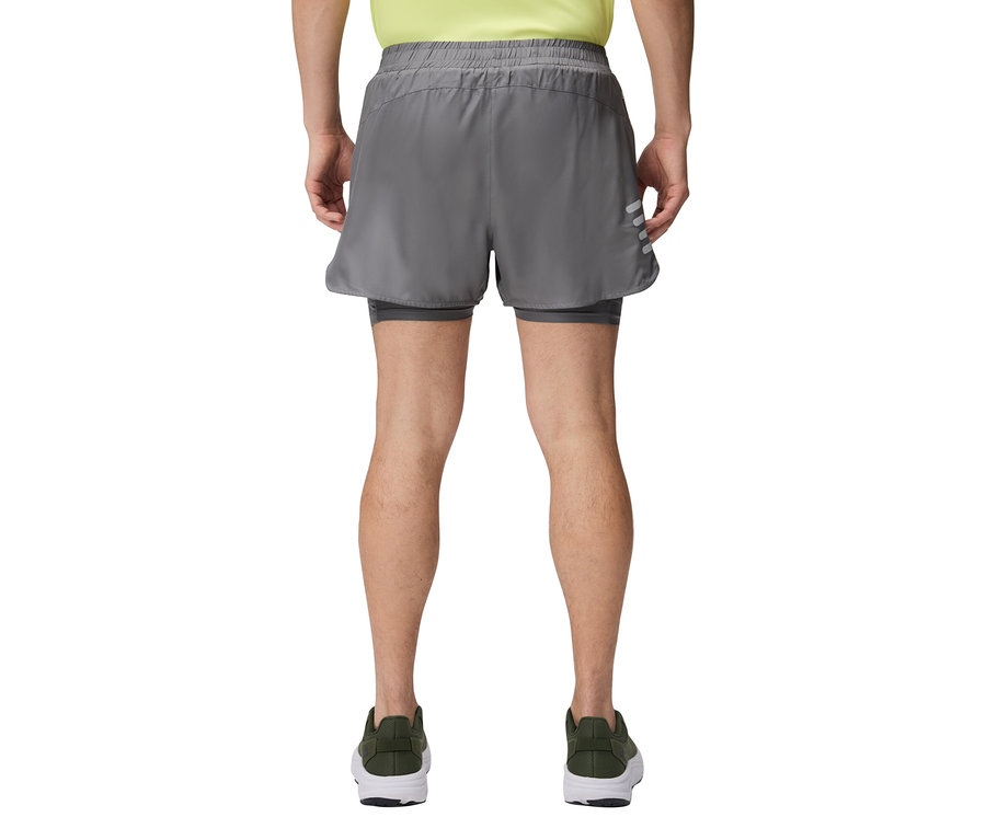 Ein Mann von hinten, der graue Shorts und grüne Schuhe trägt.