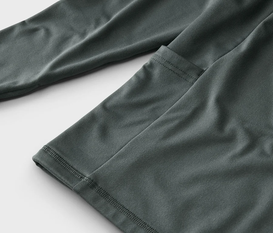Detailaufnahme eines grauen, langärmeligen Oberteils mit einer aufgesetzten Tasche.
