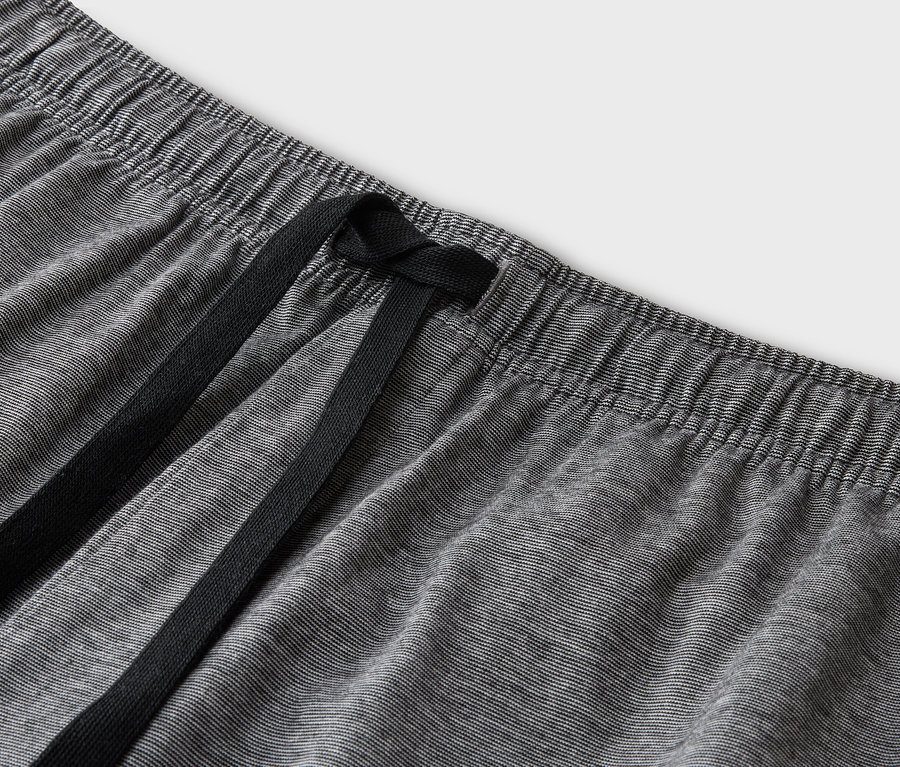 Nahaufnahme einer grauen Hose mit elastischem Bund und schwarzem Kordelzug.