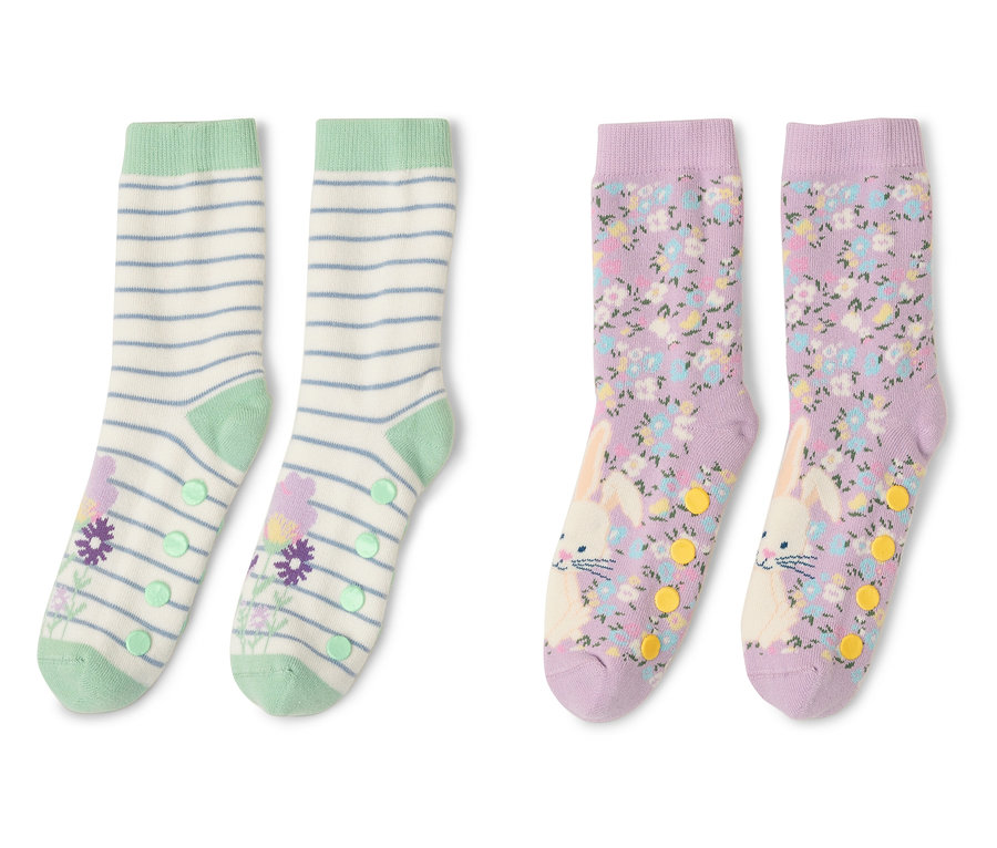 Zwei Paar Kinder-Antirutsch-Socken liegen nebeneinander. Ein Paar ist gestreift mit Blumen, das andere mit Blumen und Hasen.
