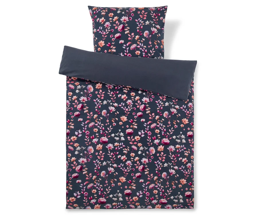 Dunkelgrauer Bettbezug mit einem Muster aus rosa, orangefarbenen und weißen Blüten und Blättern, dazu ein passender floraler Kissenbezug und ein einfarbiger dunkelgrauer Kissenbezug, der darauf gefaltet liegt.