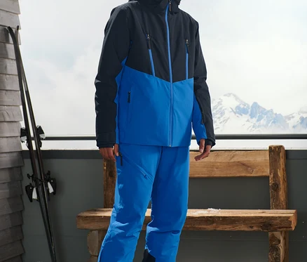 Mann steht draußen und trägt eine blaue Skijacke.