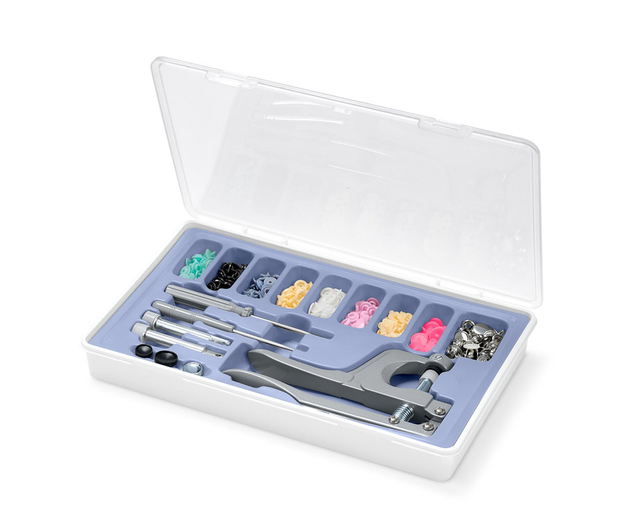 Offene weiße Schachtel mit verschiedenfarbigen Druckknöpfen und Werkzeugen zum Anbringen des Druckknopf-Sets.