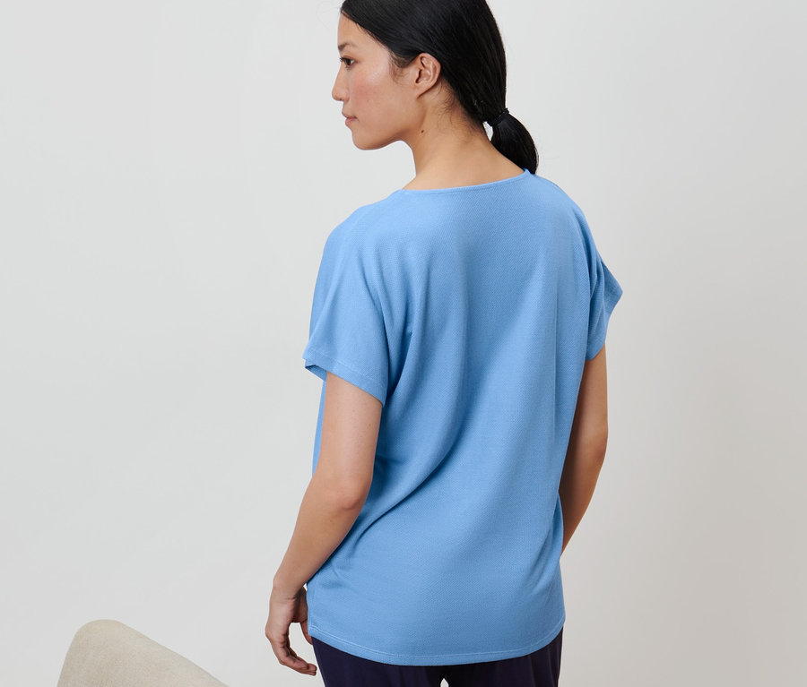Frau trägt ein hellblaues, strukturiertes Shirt.