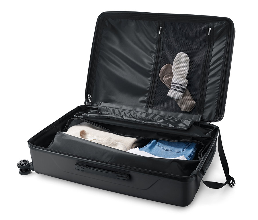 Geöffneter, großer Hartschalen-Koffer mit Kleidung darin.
