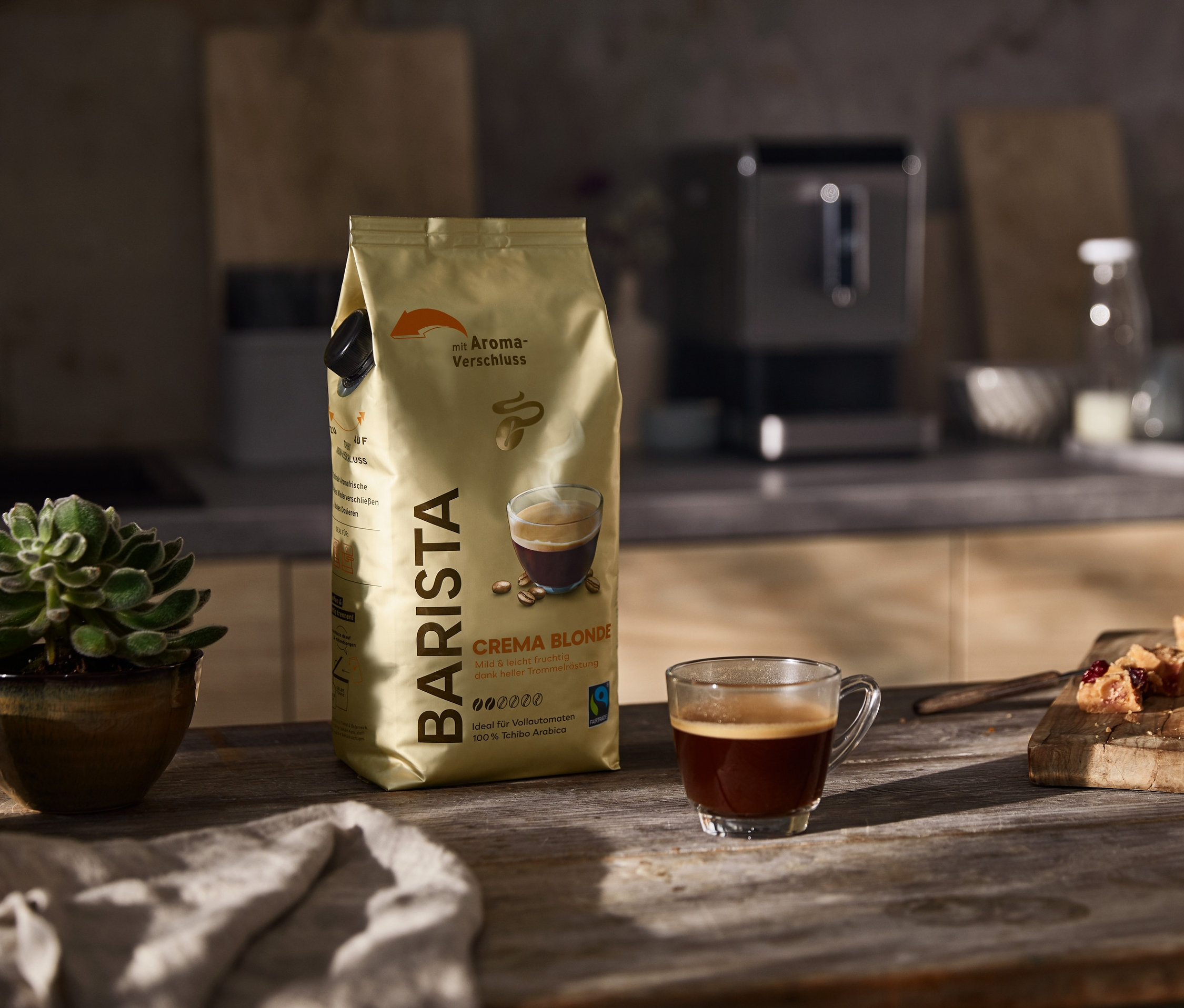 Eine Packung Barista Crema Blonde, eine Tasse Kaffee und Gebäckstücke auf einem Holztisch.