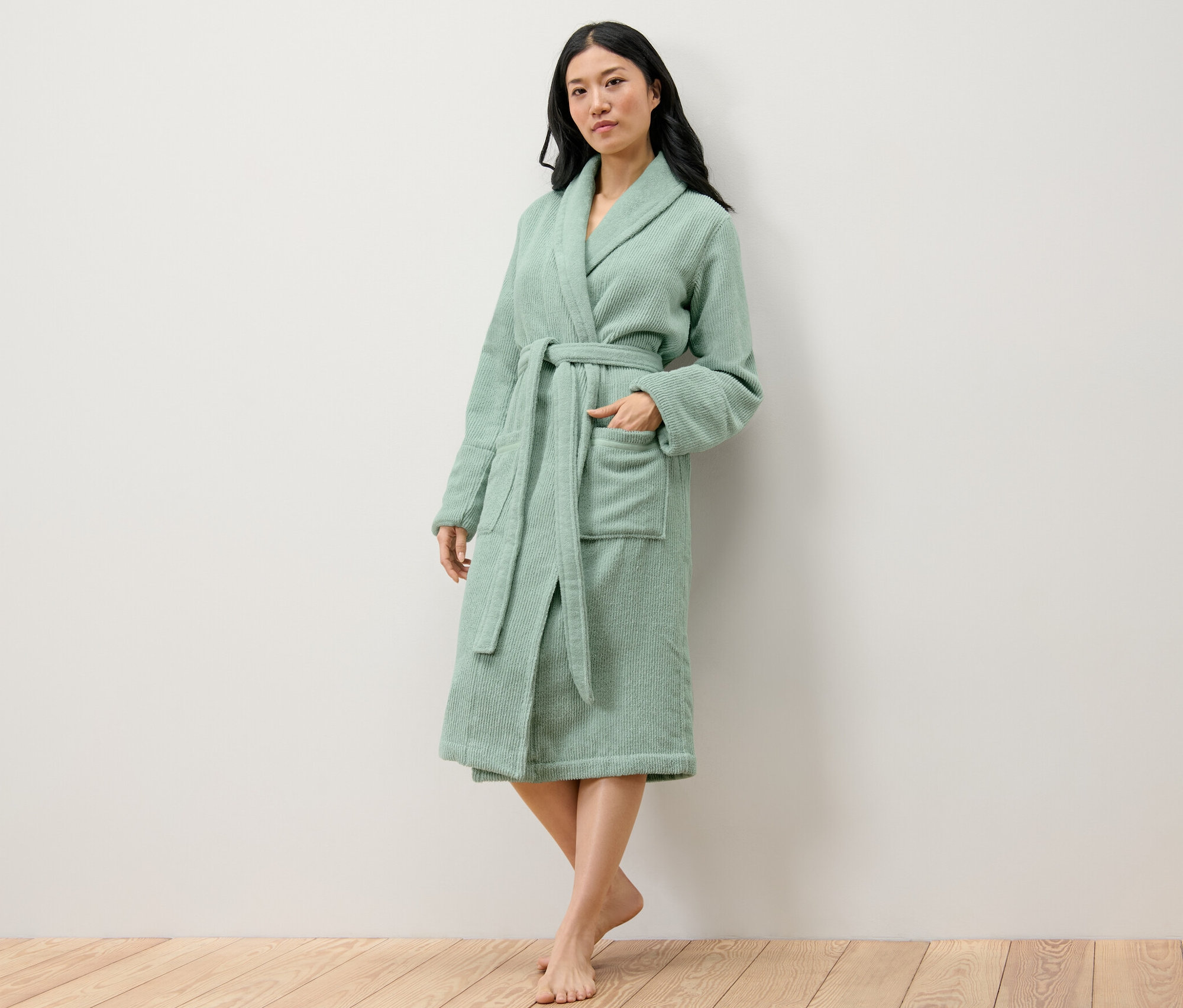 Frau posiert in einem grünen Damen-Bademantel.