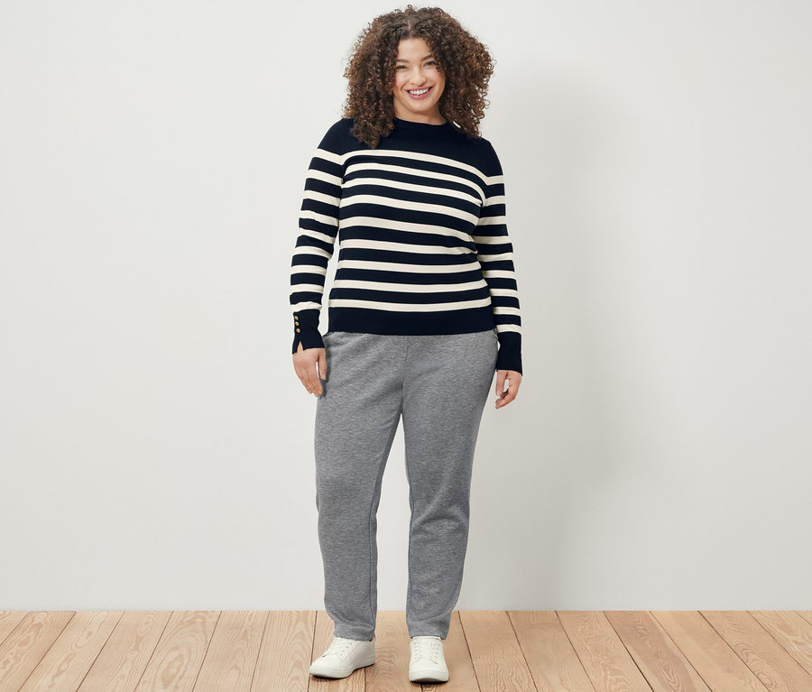 Frau trägt einen dunkelblauen, gestreiften Feinstrickpullover und eine Joggpants.
