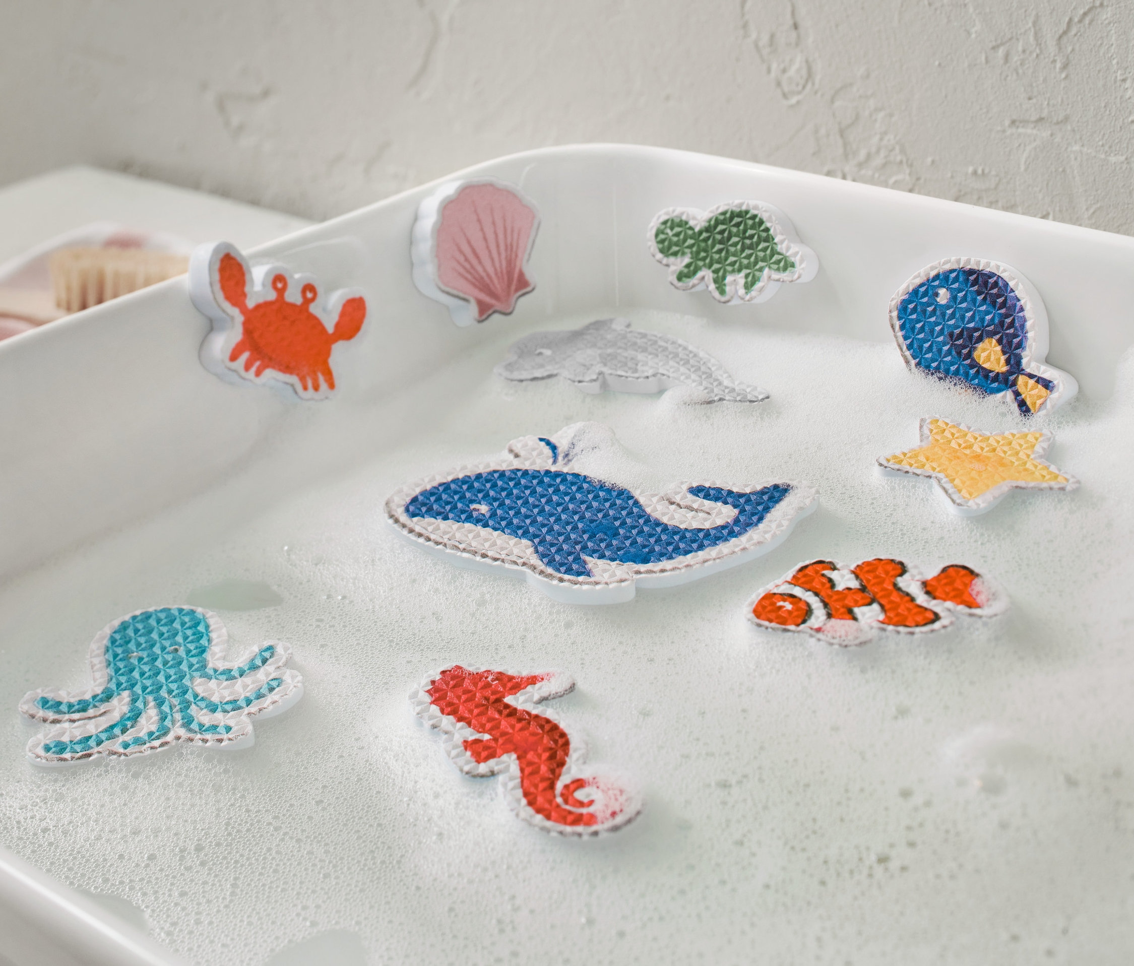 Zehn Badewannenspielfiguren »Meerestiere« liegen in einer mit Schaum gefüllten Badewanne.