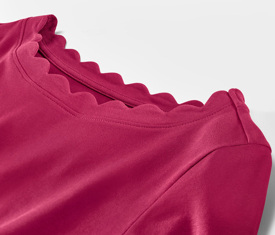 Detailansicht eines himbeerroten Shirts mit 3/4-Arm und gewelltem Halsausschnitt.