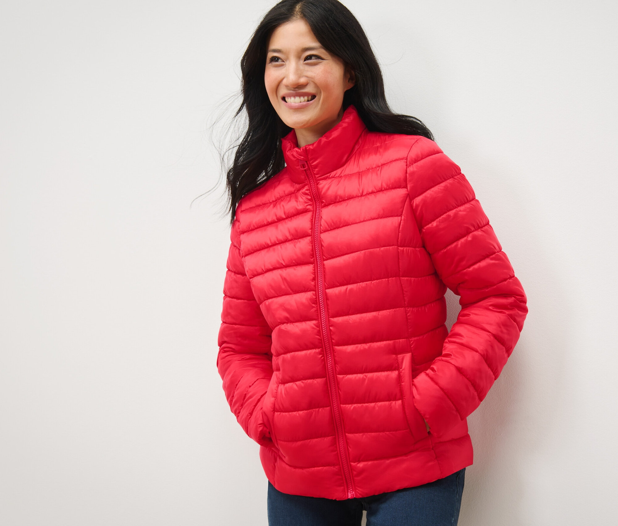 Frau lächelt und posiert in roter Steppjacke.