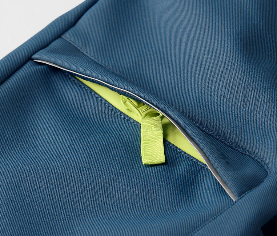 Detailaufnahme einer Kinder-Softshellhose mit neon-grünem Reißverschluss.