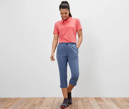 Frau trägt ein pinkes Poloshirt und blaue Funktionscapri.