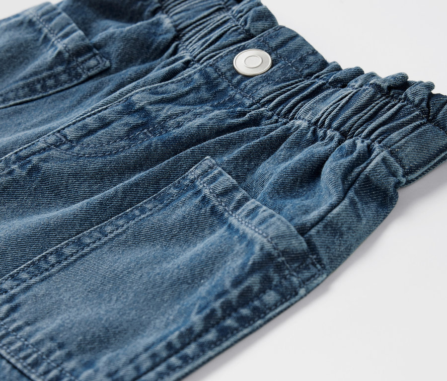 Detailaufnahme von Kinder-Jeansshorts mit elastischem Bund und Taschen.