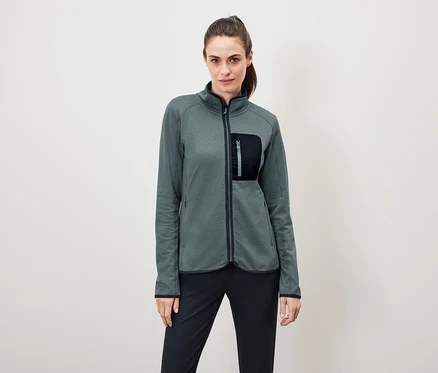 Frau trägt eine grüne Fleecejacke mit einer schwarzen Hose.