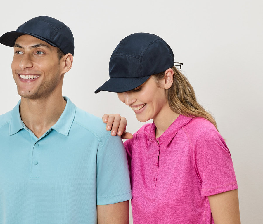 Ein Mann und eine Frau stehen nebeneinander und tragen marineblaue Kappen und Poloshirts in Blau und Pink.