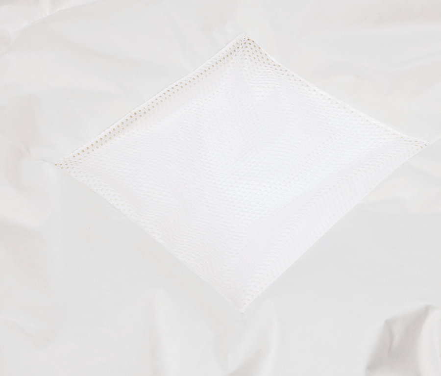 Detailaufnahme einer weißen Stofftasche mit Netzstruktur auf einem weißen Stoffuntergrund.