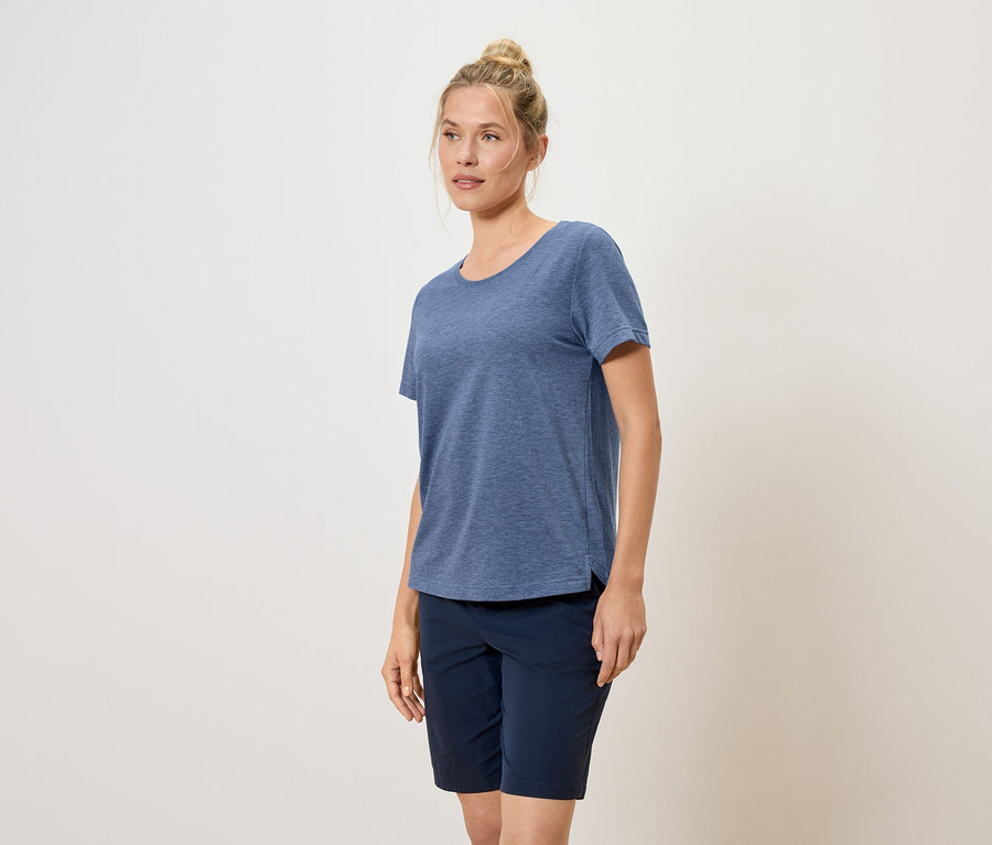 Frau mit Duttfrisur trägt blaues T-Shirt und blaue Shorts.