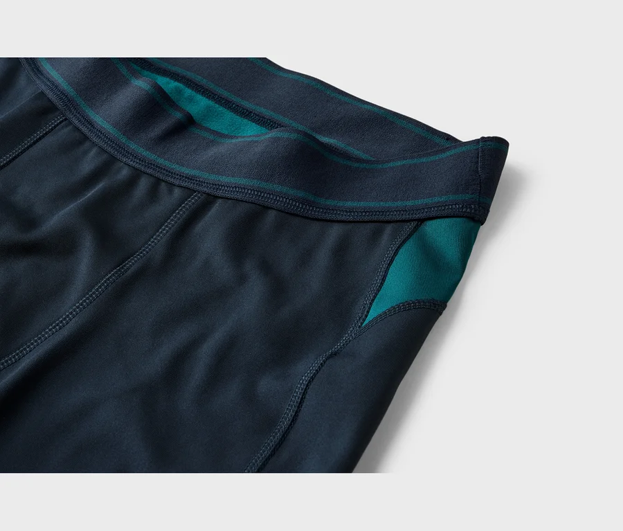 Nahaufnahme einer dunkelblauen Sporthose mit marineblauem Gummibund und türkisfarbenen Akzenten am Bund und an der Seitenpartie.