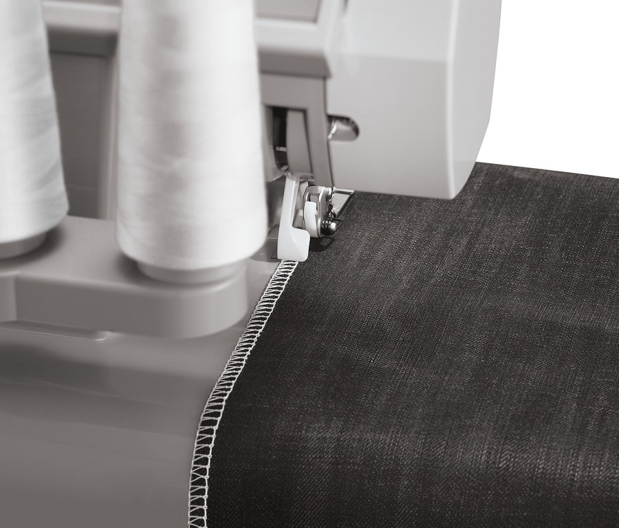 Detailaufnahme einer SINGER® Overlock-Nähmaschine »Heavy Duty 14HD854« beim Nähen von schwarzem Stoff mit weißem Faden.