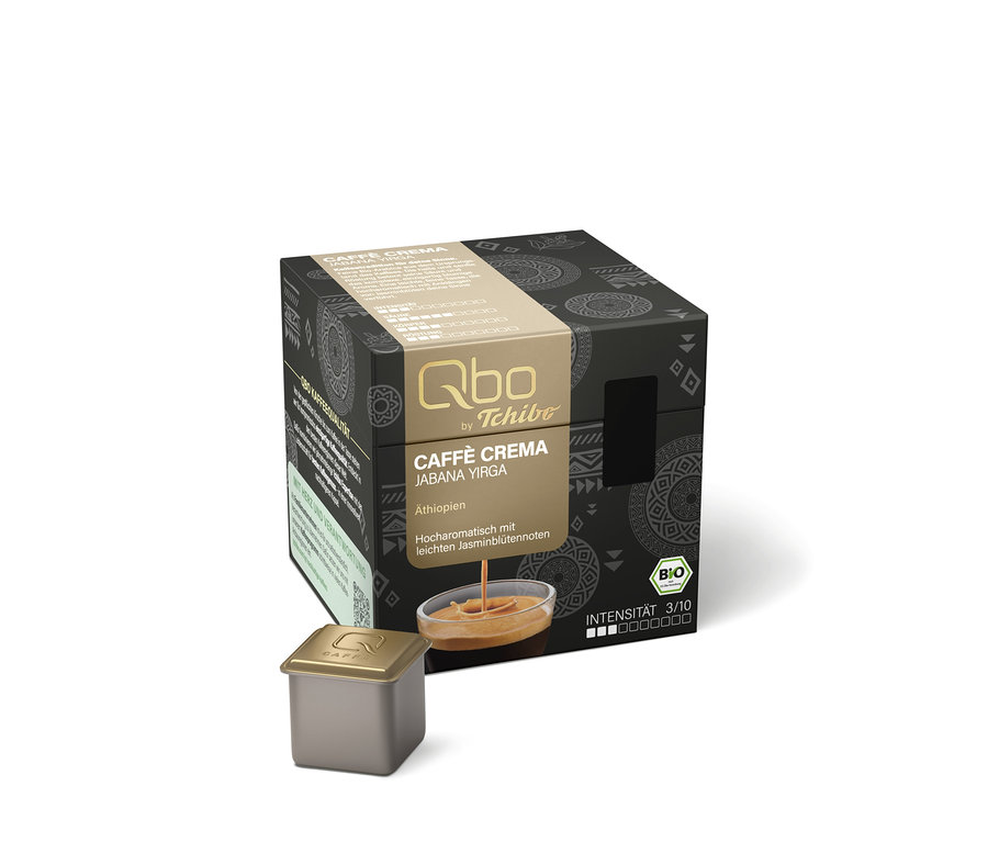 Dunkle, würfelförmige Verpackung für Qbo Caffè JABANA YIRGA Kapseln mit goldfarbenem Band, das den Produktnamen, Herkunft Äthiopien, Jasminblütennoten, BIO-Logo und Intensität 3/10 zeigt. Auf dem Band ist ein Bild von Kaffee mit Crema zu sehen. Davor liegt eine einzelne goldene Kaffeekapsel.