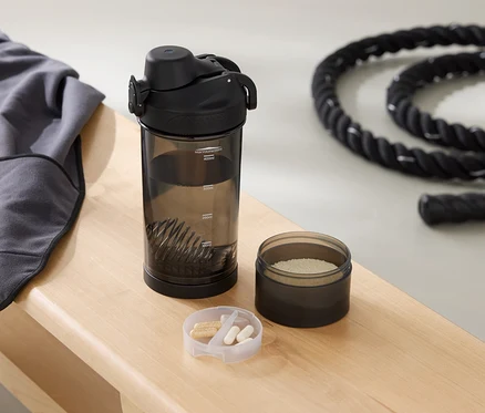 Auf einer Bank liegen ein graues Sweatshirt, eine Trinkflasche, eine Dose mit Pulver und ein Seil.