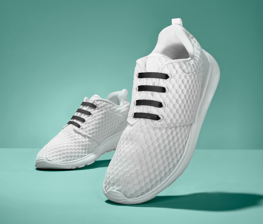 Zwei weiße Turnschuhe mit schwarzen elastischen Silikon-Schnürsenkeln. 20 elastische Silikon-Schnürsenkel.