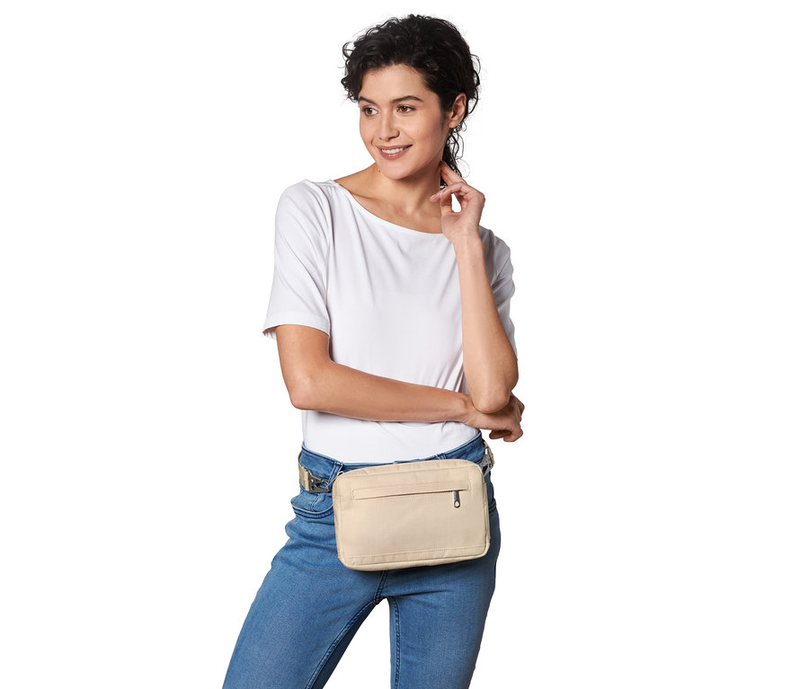 Frau posiert mit beiger Sicherheits-Gürtel- und Umhängetasche.