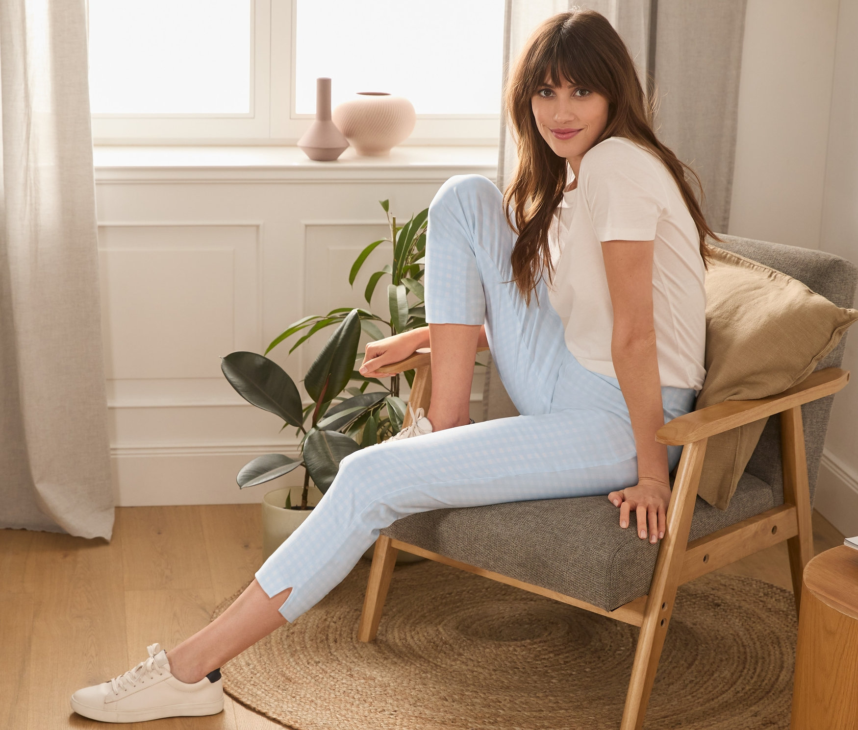 Frau sitzt im Sessel und trägt eine hellblau-weiße 7/8-Stretchhose.
