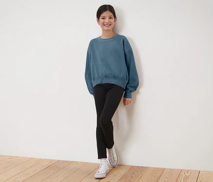 Mädchen in blauem Sweatshirt und schwarzen Kinder-Thermoleggings.