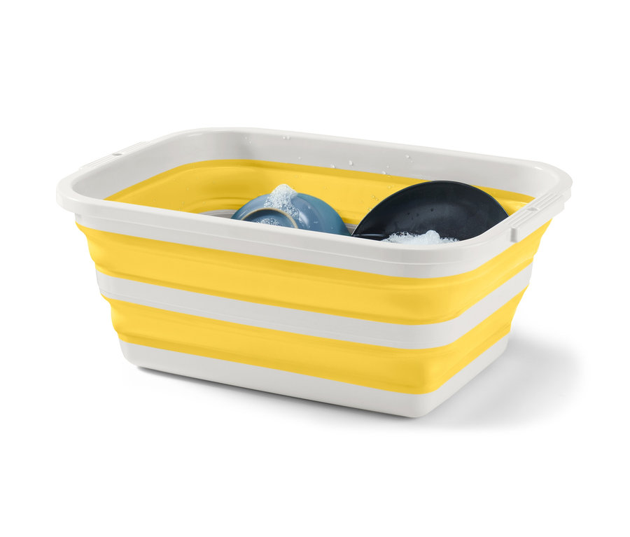 Ein faltbarer Wäschekorb in Gelb und Weiß mit Spülmittel und Geschirr darin.