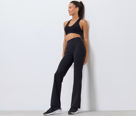 Frau posiert in schwarzem Sport-BH und Bodyforming-Sporthose.