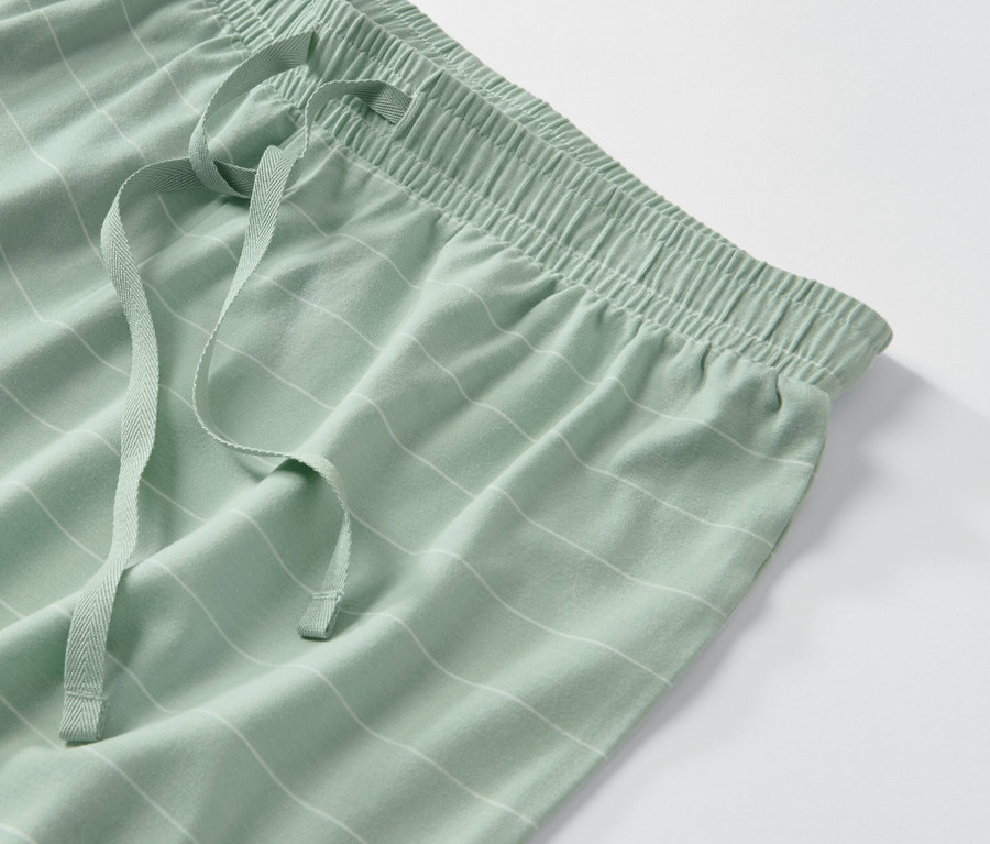 Detail einer grünen Pyjamahose mit weißen Streifen und Kordelzug.