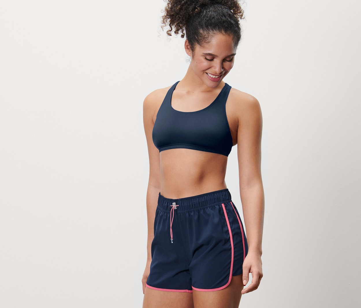 Lächelnde Frau trägt Badeshorts und Sport-BH.