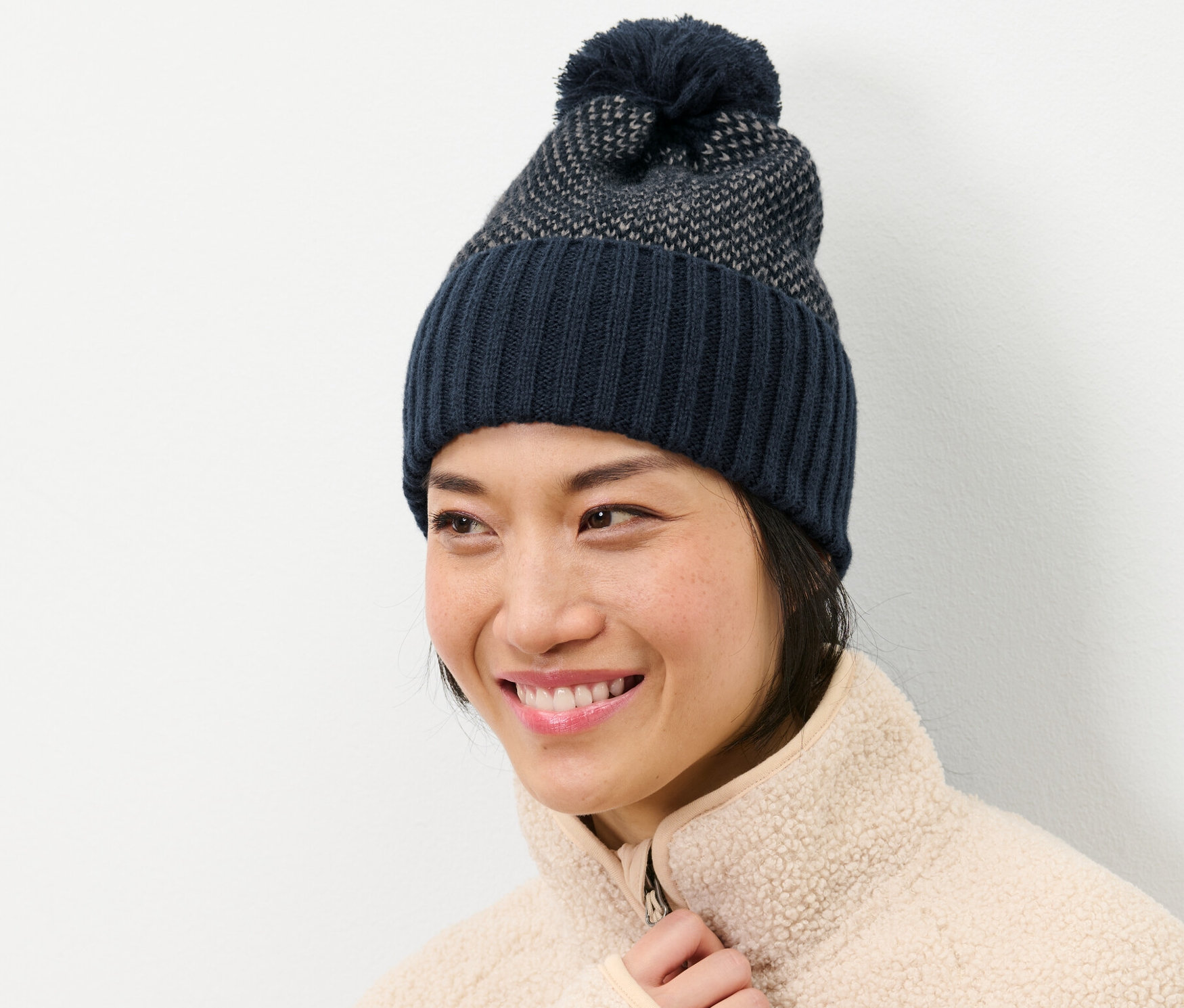 Frau lächelt und trägt eine Strickmütze.