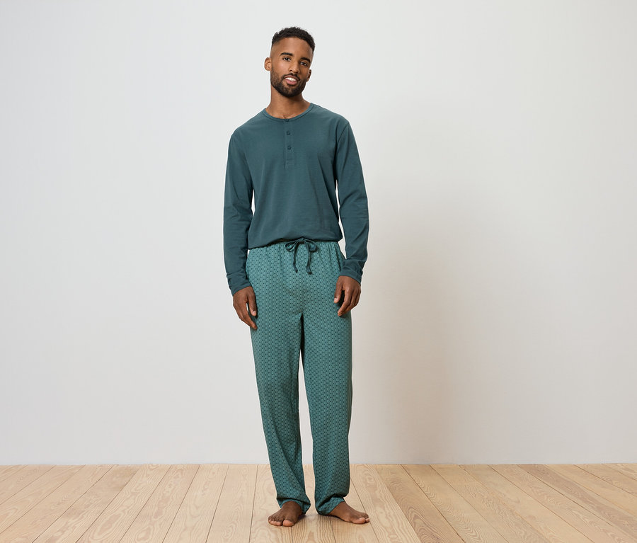 Mann steht und trägt einen grünen Schlafanzug.