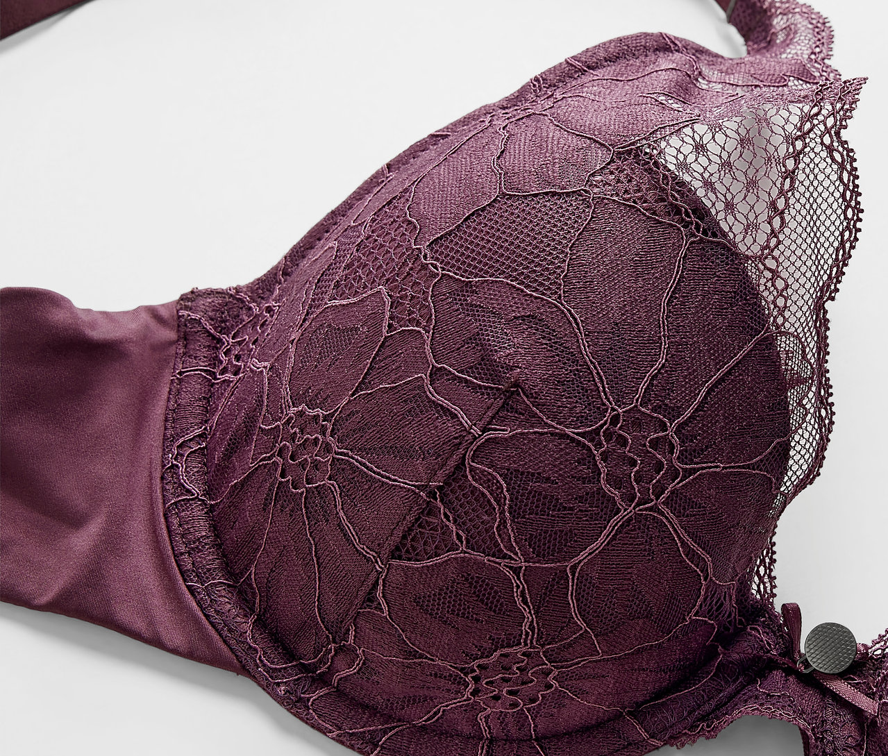 Detailaufnahme eines lila Schalen-BHs mit Blumenspitze.