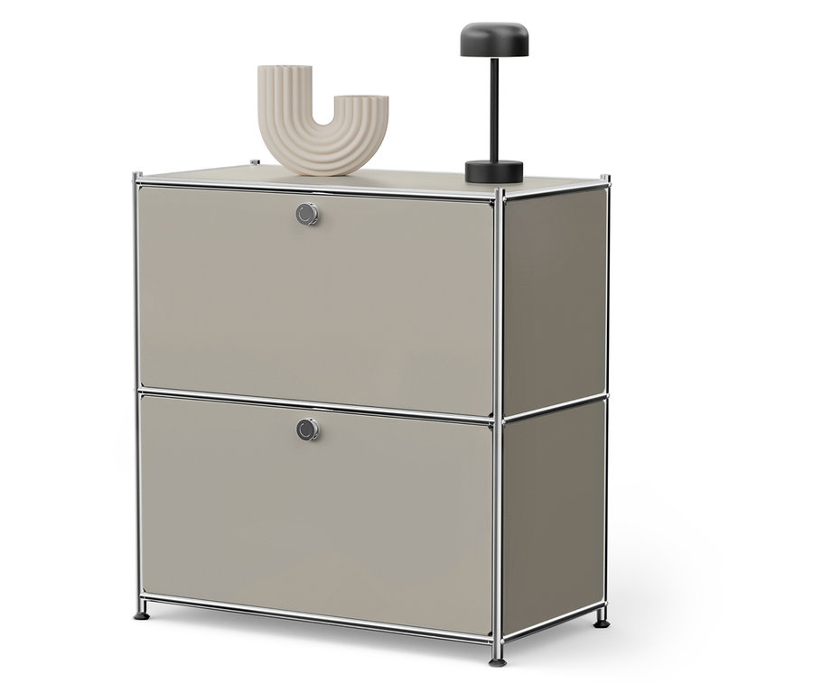 Beiger Schrank mit zwei Schubladen, darauf Vase und Lampe.