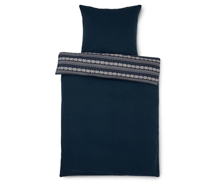 Dunkelblaue Bettwäsche mit Kissen und Überwurf mit weißem Schneeflockenmuster.
