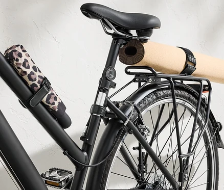 Schwarzes Fahrrad mit Yogamatte und Regenschirm, befestigt mit 6 elastischen Befestigungsgurten.
