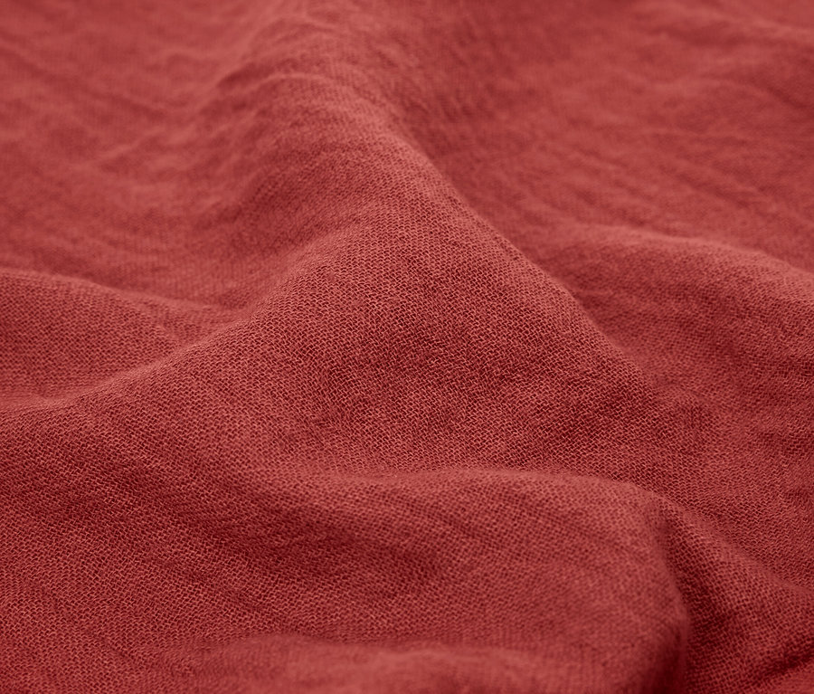 Nahaufnahme von zwei ziegelroten Musselin-Handtüchern.