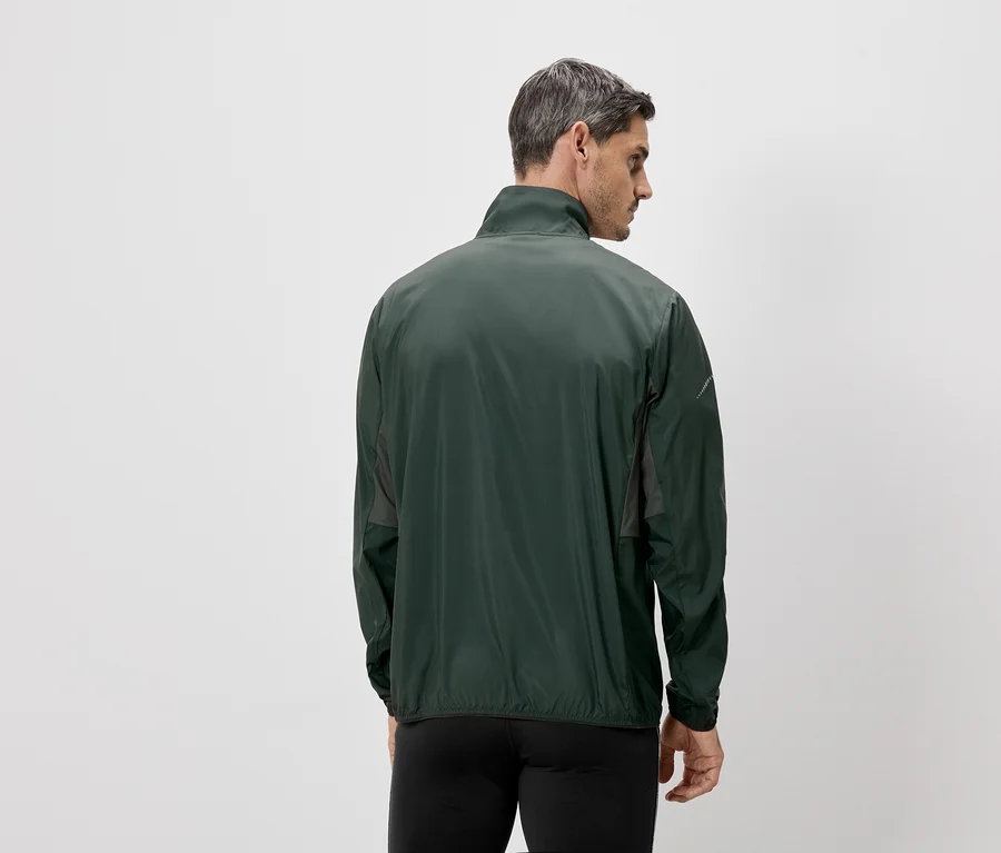Mann von hinten, mit grüner Jacke und schwarzer Hose vor einem weißen Hintergrund.