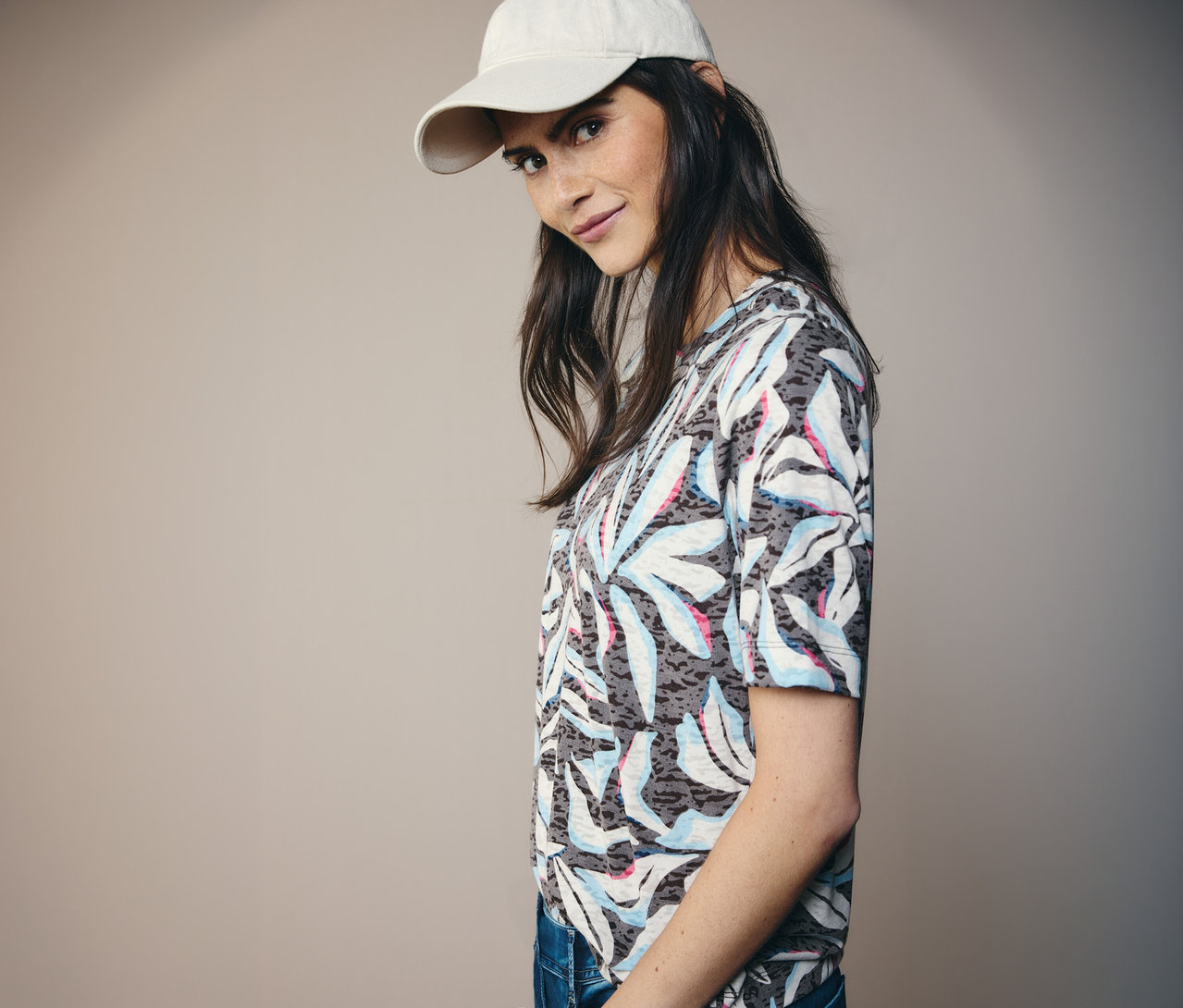 Frau mit beiger Kappe und blauem CECIL Kurzarmshirt mit Blätterdruck.