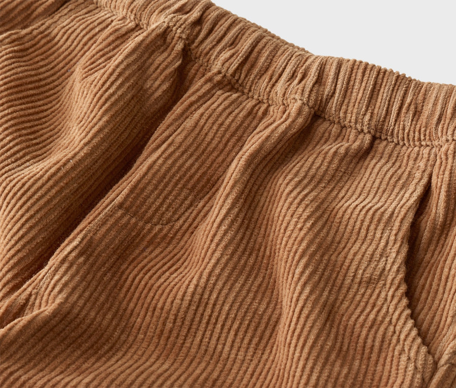 Nahaufnahme einer hellbraunen Cordhose mit elastischem Bund und einer seitlichen Eingrifftasche.