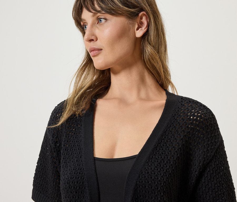Frau trägt eine schwarze, gehäkelte Strickjacke.